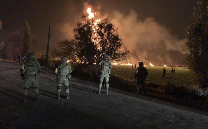 Soldati dell'esercito messicano guradano le fiamme, pronti ad intervenire dopo l'esplosione dell'oleodotto in Messico.