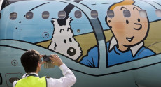 Un visitatore della mostra fotografa un poster di Tintin con il suo cane.