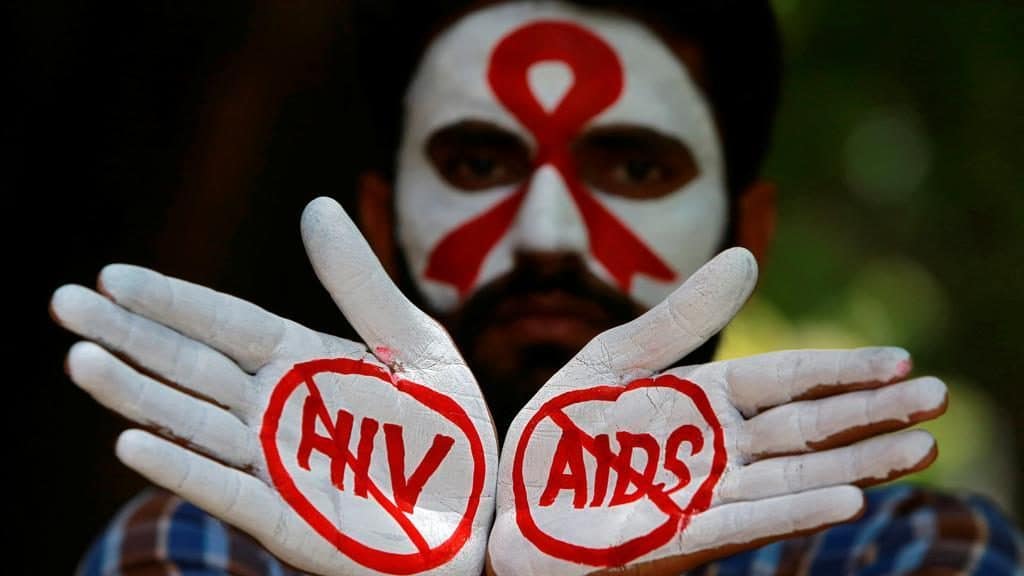Una faccia truccata di bianco con il simbolo Aids e sulle mani aperte le scritte HIV e AIDS