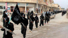 Plotone di soldati dell'Isis sfila con la bandiera nera. Archivio