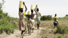 Bambine africane con bidoni di acqua in testa.