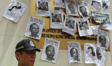 Cina: un oppositore del governo con le foto di persone scomparse.