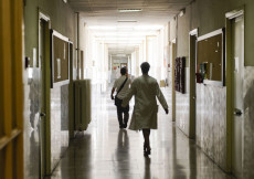 Un medico (ripreso di spalle) camminando in una corsia d'ospedale.