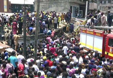 La folla dei genitori intorno alle macerie della scuola crollata in Nigeria.