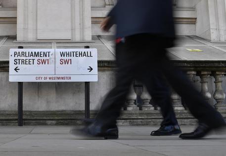 Persone camminando vicino alla segnaletica che indica la direzione della Whitehall a Londra.