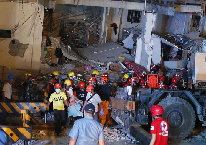 Primi soccorsi e pompieri su alcune macerie si un edificio dopo il terremoto a Manila,.