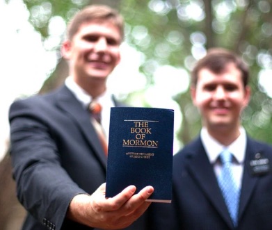 Il libro dei mormmoni in primo piano, mostrato da due fedeli.