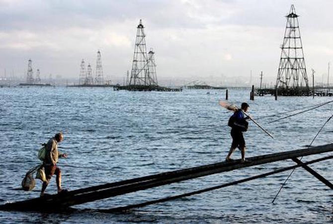 Due pescatori camminano su una passerella davanti ai pozzi di petrolio nel Mar Caspio, vicinanze di Baku, Azerbaijan.