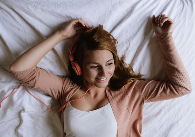 Risveglio: Ragazza a letto con le cuffie ascoltando musica.