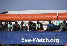 Migranti affacciati al parapetto della Sea Watch.