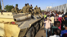 Militari su un carro armato e civili per strada festeggiano la caduta del dittatore al-Bashir.