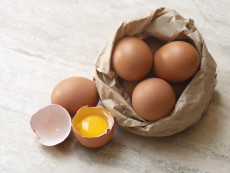 Una composizione di uova in un cestino, un uovo aperto.
