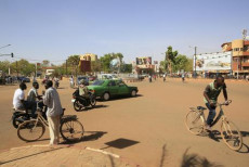 Scene di vita domenicale nella United Nations Square in Ouagadougou, Burkina Faso: gente in bicicletta e un'automobile in piazza.