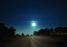 Luna piena all'orizzonte illumina una strada solitaria.