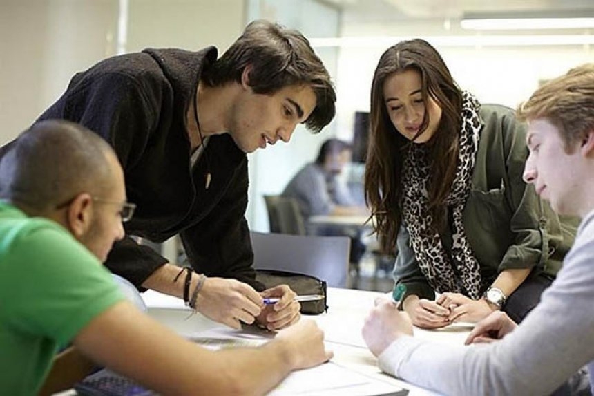 Adolescentes reunidos alrededor de una mesa y estudiando