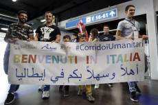 Ragazzi ricevono rifugiati arrivati in Italia attraverso i corridoi umanitari con un striscione di Benvenuti.
