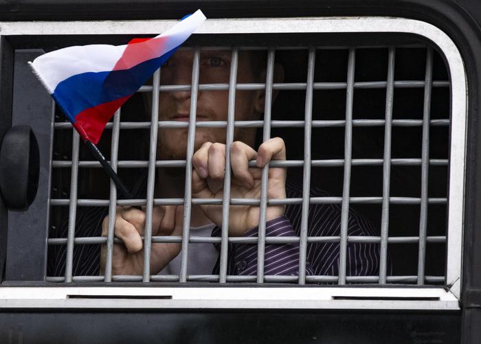 Uno dei detenuti durante la manifestazione per la liberazione di Golunov, mostra la bandierina russa da dietro le grate.