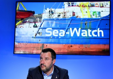 Il vice Premier e Ministro degli Interni, Matteo Salvini. Alle sue spalle un video con la Sea-Watch.