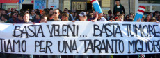 Manifestanti contro l'inquinamento dell'Ilva a Taranto esibiscono uno striscione.