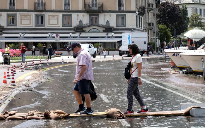 Turisti utilizzano una passerella in piazza Cavour allagata a causa dell'esondazione del lago, Como,.