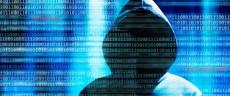 Sagoma di una persona con cappuccio riflessa sullo schermo di un computer personificando un "hacker" .