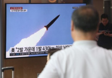 Una persona segue sullo schermo della tv il lancio del missile del Nord Corea.