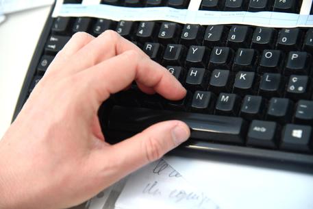 Un impiegato lavora al computer nel suo ufficio digitando su una tastiera di computer.