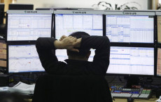 Un trader guarda su una serie di monitor l'andamento dei cambi alla Borsa di Pechino.
