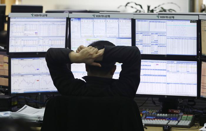 Un trader guarda su una serie di monitor l'andamento dei cambi alla Borsa di Pechino.