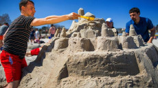 Due persone costruendo castelli di sabbia sulla spiaggia.