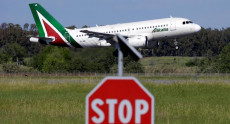 Un aereo di Alitalia e in primo piano un cartello di STOP