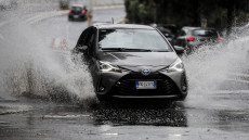Maltempo, un'automobile percorre una via di Roma allagata per la pioggia.