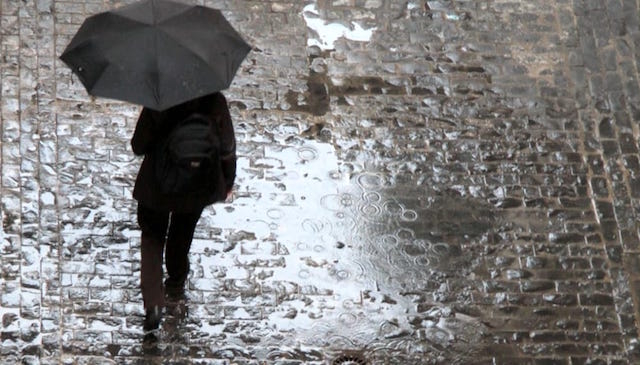 Persona con ombrello sotto la pioggia.