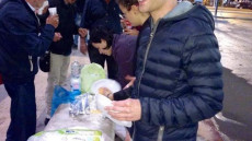 Volontari distribuiscono da mangiare a senzatetto.