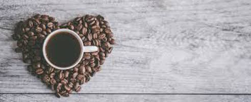 Una tazzina di caffè in un cuore di chicchi di caffè.