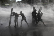 Cile, dimostranti durante le proteste a Santiago nel fumo dei lacrimogeni.