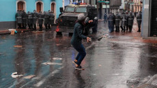 Ecuador: un giovane lancia pietre contro blindato dell'esercito durante le proteste.