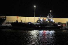 Motovedetta attracca di notte sul porto di Lampedusa con il suo carico di migranti.