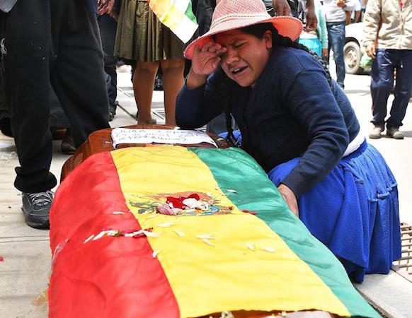 Bolivia, una donna piange sulla bara di un congiunto.
