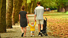 Padre, madre e bambino: una famiglia a spasso in un parco.