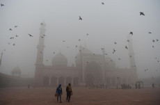 Pedoni camminano a Nuova Delhi in mezzo a una nuvola di smog.