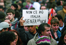 Migranti che lavorano in Italia con un cartello ad una manifestazione.