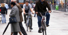 Milanesi passeggiano a piedi e in bicilcetta per una strada deserta nel centro di MIlano.