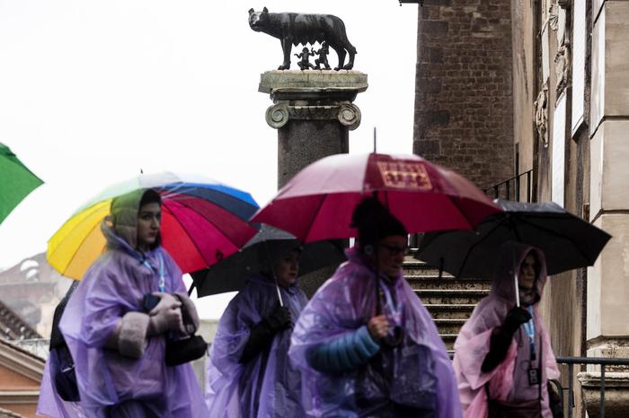 Turisti si riparano dalla pioggia in Campidoglio per il maltempo sulla Capitale,