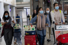 Viaggiatori portano mascherine nella Hall dell'aeroporto internazionale di Hong Kong.