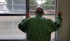 Un detenuto guarda l'area esterna attraverso le sbarre della cella.