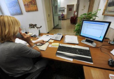Impiegata della Pubblica amministrazione nel suo posto di lavoro davanti ad un computer.