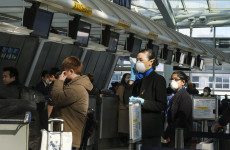 Passeggeri con la mascherina controllano gli orari della China Eastern nell'aeroporto John F. Kennedy di NY.