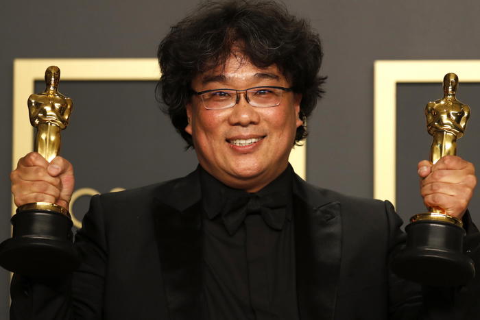 Oscar, Bong Joon Ho posa con le due statuette vinte agli Oscar 2020 dal suo film Parasite.