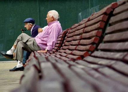 Pensionati siedono in panchina in una piazza.